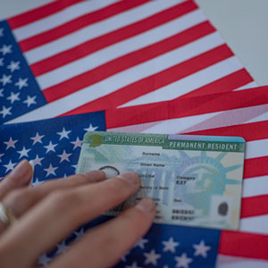 Woman touching a U.S. permanent residency card on top of two U.S. flags - Phillip A. Roach Attorney At Law